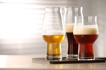Glasses with different types of beer on wooden table indoors, space for text