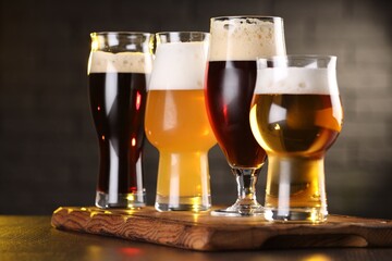 Glasses with different types of beer on wooden table in bar, closeup