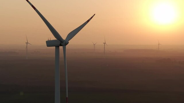 Farma wiatrowa na tle zachodzącego słońca, wiatrak, energia odnawialna