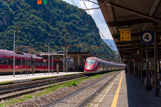 Red and silver colored high speed train named Frecciarossa arriving at railway station of Italian City of Bozen on a sunny summer day. Photo taken July 17th, 2024, Bolzano Bozen, Italy.
