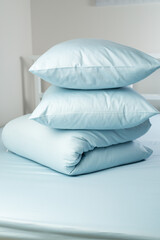 A set of blue bed linen, neatly folded in a pile: a pillow in a pillowcase and a blanket in a duvet...