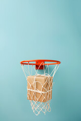 Giftbox is falling in basketball hitting net. A parcel wrapped in craft paper is falling inside the basketball hoop. Success in action, right choice, good work concept. High quality delivery service