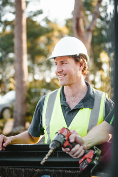 Two builders standing next to the ute, one holding a drill.