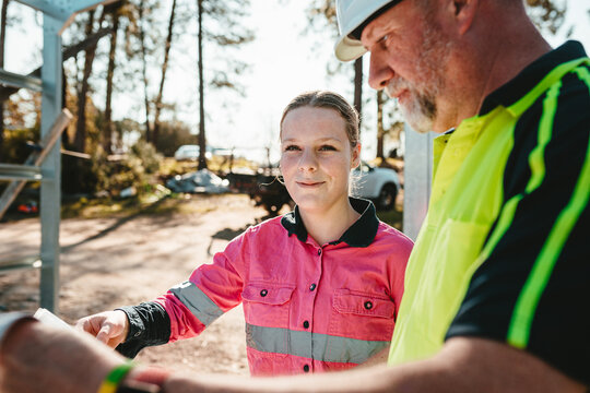 Young woman smiling while the man looks at the blueprint.