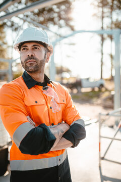 A bearded contractor standing with arms crossed.