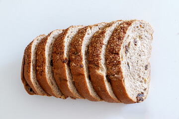 Top view of slices of healthy whole grain raisin and walnut brown bread on white background, in order of size, smallest to largest, healthy eating and lifestyle concept