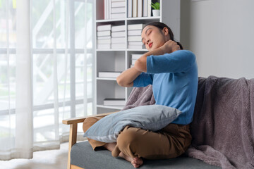 A woman is sitting on a couch with a pillow behind her back