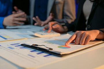 A group of people are looking at a table with a lot of papers and a calculator