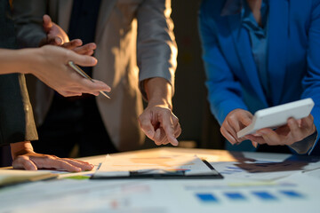 A group of people are gathered around a table with papers and a calculator