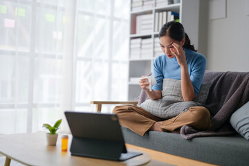 A woman is sitting on a couch with a laptop in front of her