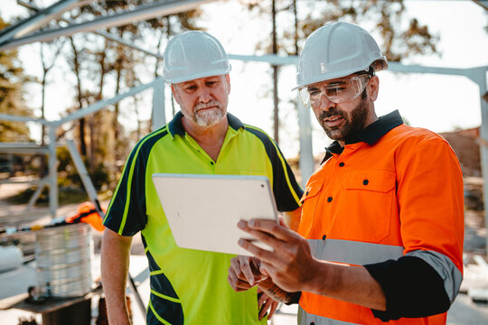 Two construction site managers looking at digital blueprints on tablet device