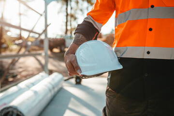 Construction worker holding a white helmet at construction site.