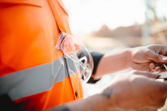 Safety glasses hanging on the builders protective clothing.
