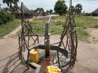 A simple hand pump water well provides clean water in a rural village in South Sudan.