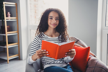 Photo of nice young girl sit armchair reading interesting book wear striped clothes enjoy modern cozy interior flat indoors