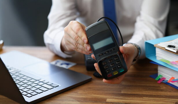 Close-up of man holding modern credit card reader machine for cashless payment. Empty screen for total cost and numbers on pad. Modern technology concept