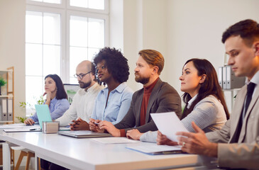 Team of business professionals communicating during a meeting, conference, or presentation in the office. Teamwork and collaboration, showing people working together in a business environment.