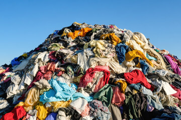 Fototapeta premium Enormous pile of discarded clothing under a clear blue sky