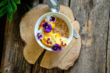 Oatmeal with peaches and flowers. Wooden background, rustic