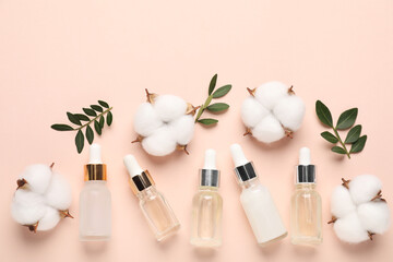 Different cosmetic products, cotton flowers and green leaves on beige background, flat lay