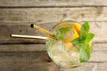 Glass of tasty refreshing drink and straws on wooden table, top view