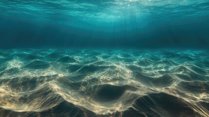 Underwater photo capturing sunlit sand dunes at the sea floor with turquoise water in the distance creating an abstract marine backdrop