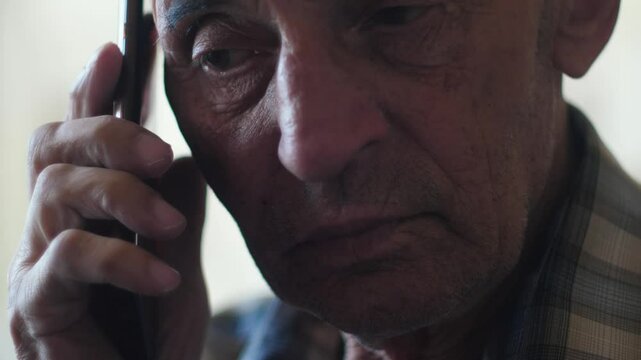 portrait of serious Caucasian elderly man 70-75 years old talking on the phone, concentrated pensioner talking on the phone listening to the interlocutor