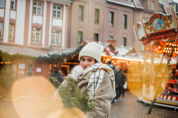 Happy young woman of European appearance at Christmas market in Germany. Festive city. Decor. New Year. Winter holidays.