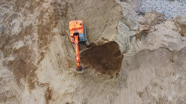 Top down view of excavator loading dump truck on construction site. Excavator is digging hole in ground