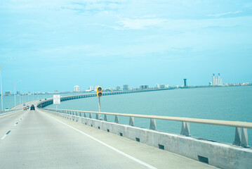 Obraz premium Traffic light over The Queen Isabella Memorial Bridge or Queen Isabella Causeway with downtown South Padre Island buildings in background, concrete pier-and-beam bridge from Port Isabel, Texas