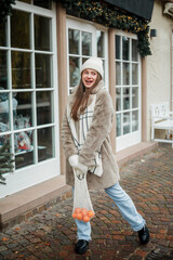 Happy young woman of European appearance at Christmas market in Germany. Festive city. Decor. New Year. Winter holidays.