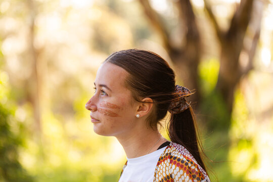 Side profile of teen aboriginal girl looking up wearing traditional ochre face paint