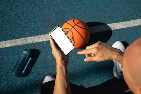 Basketball player using smartphone and social media during game interval. Sports mock up. View from above. - Powered by Adobe