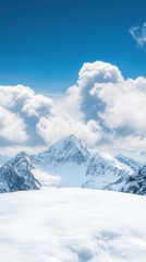 Obraz premium Majestic snow-covered mountain landscape under a bright blue sky with clouds.