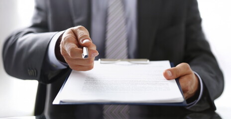 Close-up of businessman propose to sign paper, give silver pen to make deal on document. Prepared business papers for client. Business, success concept