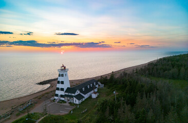 West Point lighthouse stands prominently on the coastline as the sun sets over the calm ocean...