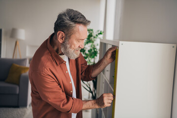 Fototapeta premium Photo of nice retired man repair install shelf wear brown clothes modern cozy interior flat indoors