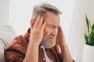 Photo of nice pensioner man sit couch touch temples headache dressed brown garment spend pastime...