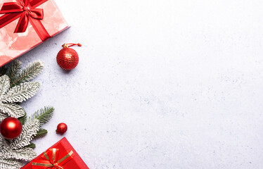 Christmas border with fir tree branches, gift boxes and shining decorations on gray concrete background with copy space for your design.
