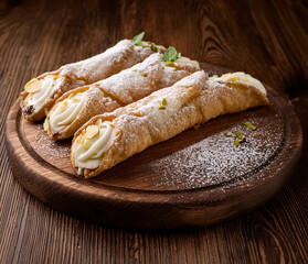 Cannoli on a rounded wooden tray.  Italian traditional pastry dessert