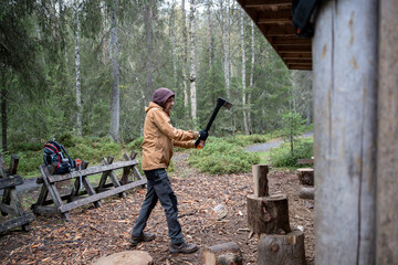 man chopping firewood with an axe for making a fire in the forest