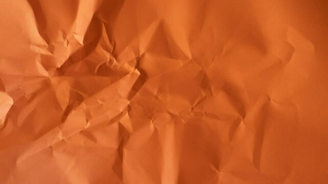 Crumpled and creased orange-brown paper video background, textured paper backdrop
