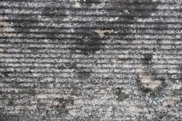A close-up view of an old asbestos roof, showcasing its rough, weathered texture. The image highlights the aged material and worn details