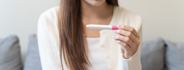 Close-up young woman checking on the pregnancy test and the result is positive.