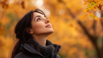 Young woman looking up with autumn leaves in the background.