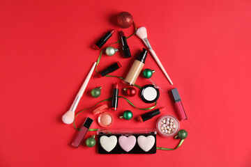 Christmas tree made with makeup products and decor on red background, flat lay