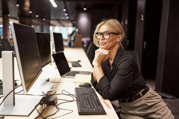 A Professional Woman Engaged in Her Work at a Modern Office with a Computer and Laptop