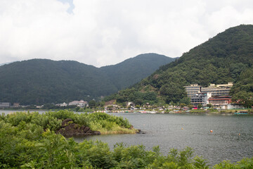 These are the rolling hills of Fujiyoshida, which is a small village nestled in Japan. The clouds look to be just floating past them. Lake Kawaguchi is shown below, which usually looks quite placid.