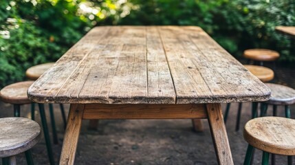 Fototapeta premium Weathered wooden picnic table with a chipped surface, surrounded by mismatched stools in a sunny garden setting