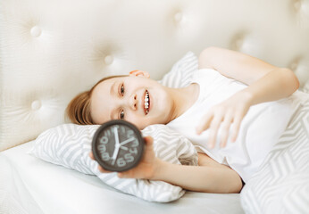 Alarm clock on bed. Kid boy teenager lies on the bed and smiles